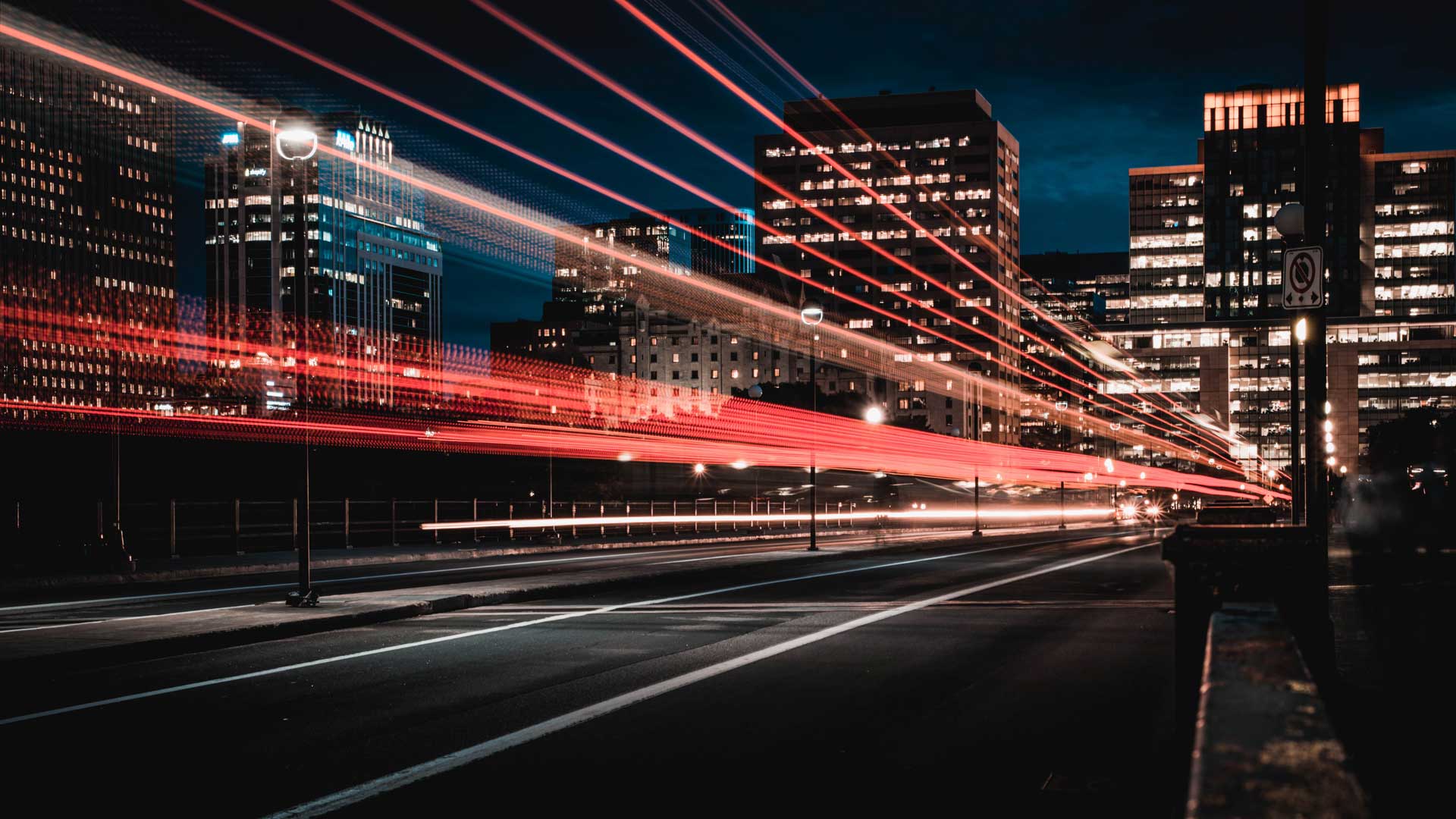 Long exposure of a city street at night with white headlight trails and red taillight trails